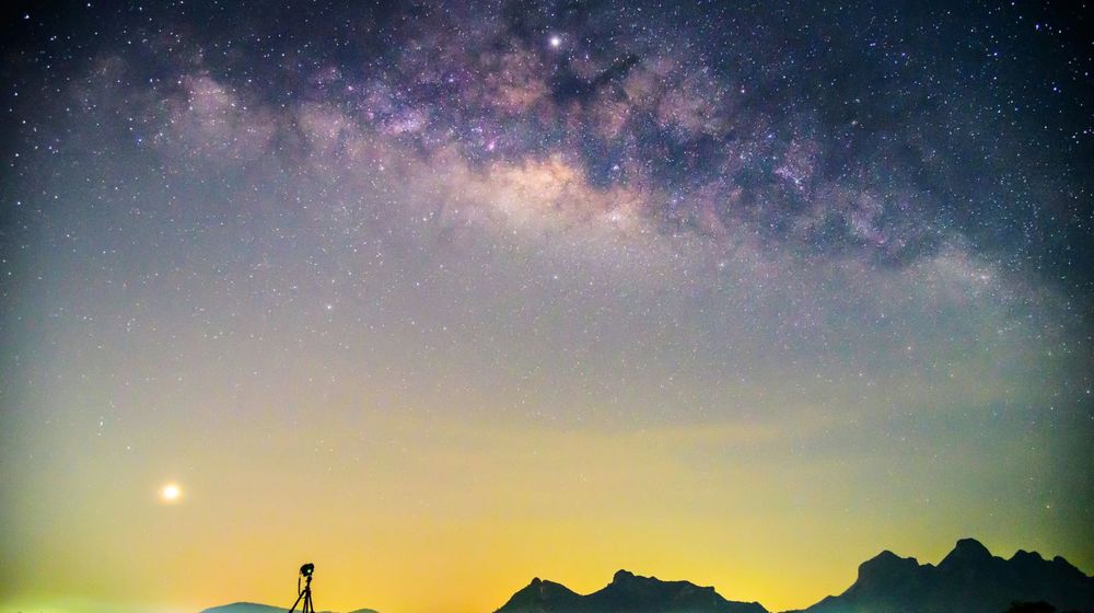 Appareil photo sur trépied pointé vers le ciel étoilé, une base d'astrophotographie pour débutant